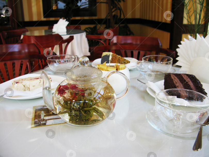 Скачать Чайник с чаем и десертом на столе в кафе фото фотосток Ozero