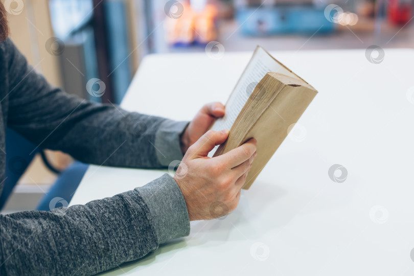 Скачать Молодой человек читает открытую старую бумажную книгу фотосток Ozero