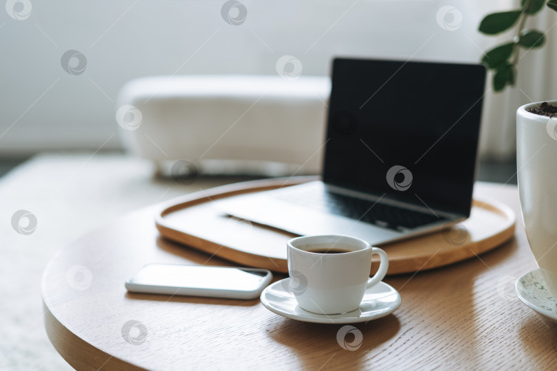 Скачать Рабочее место с чашкой кофе, открытый ноутбук на деревянном столе в офисной комнате, деловой интерьер фотосток Ozero
