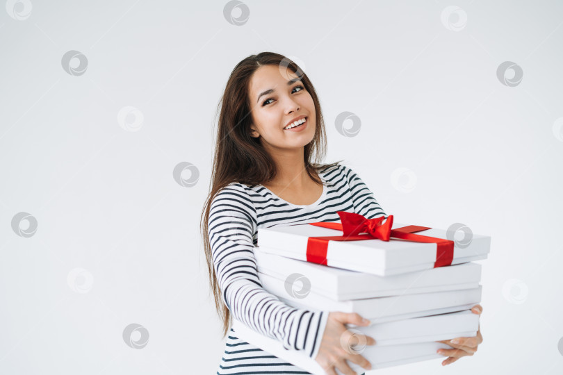 Скачать Портрет молодой улыбающейся азиатской женщины со стопкой подарочных коробок в руках на белом фоне изолированно фотосток Ozero