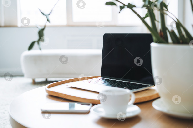 Скачать Рабочее место с чашкой кофе, открытый ноутбук на деревянном столе в офисной комнате, деловой интерьер фотосток Ozero