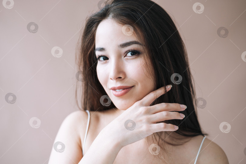 Скачать Красивый портрет молодой азиатской женщины со здоровыми темными длинными волосами на изолированном бежевом фоне фотосток Ozero
