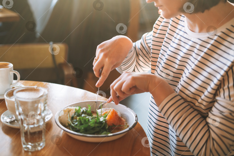 Скачать Молодая женщина завтракает полезным завтраком за столиком в утреннем кафе фотосток Ozero