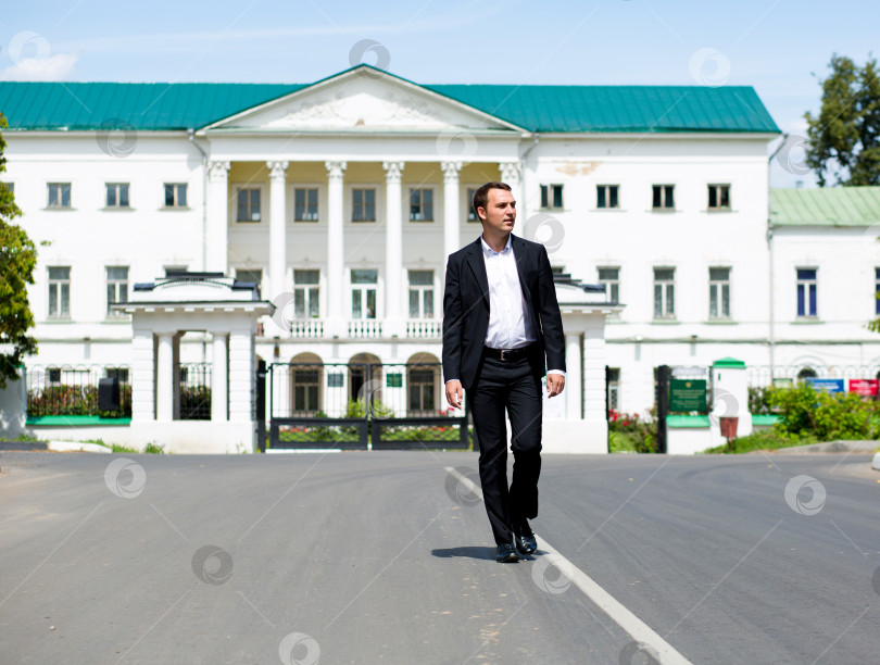 Скачать Портрет молодого бизнесмена в полный рост, идущего по дороге фотосток Ozero