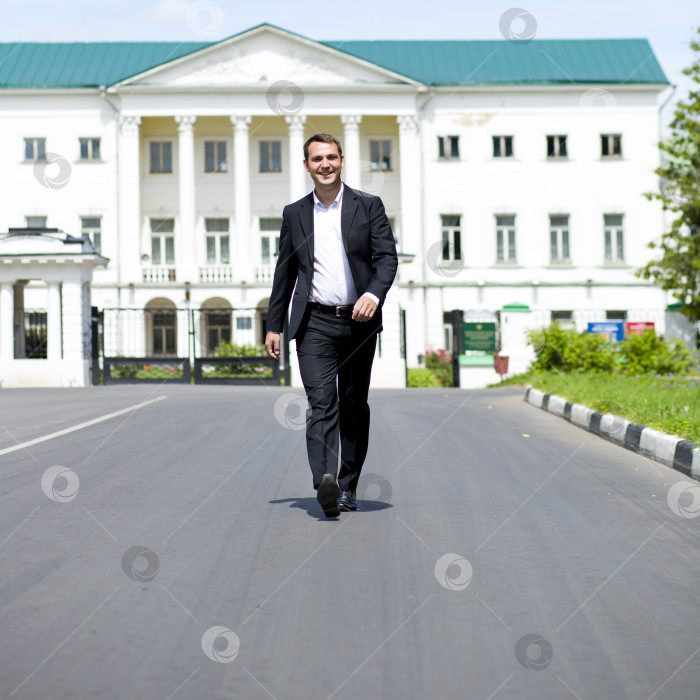 Скачать Портрет молодого бизнесмена в полный рост, идущего по дороге фотосток Ozero