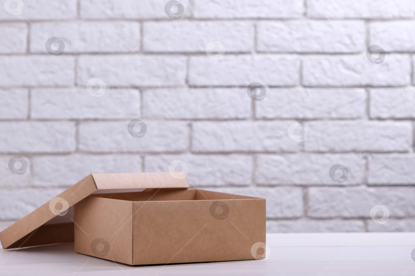 Скачать Коробка из крафт-картона на столе на фоне кирпичной стены фотосток Ozero