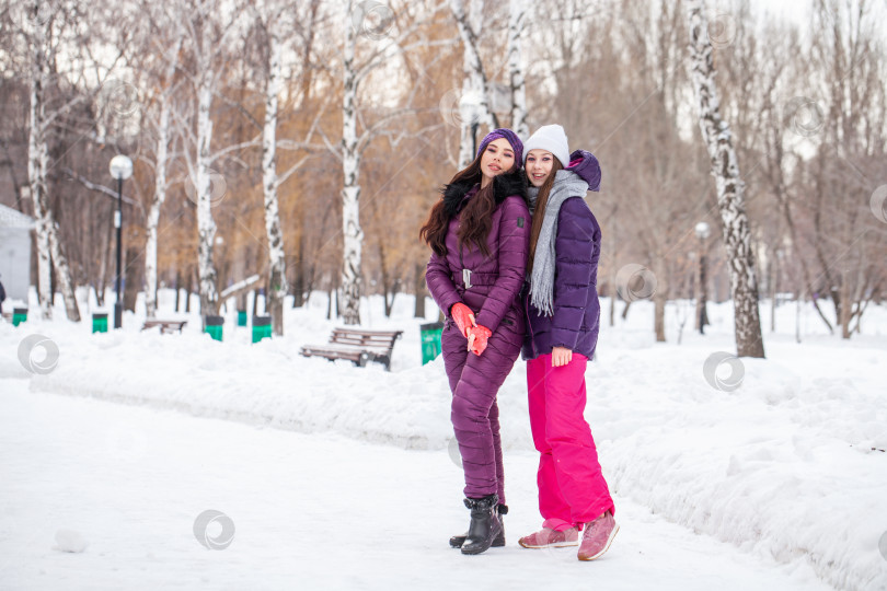 Скачать Две молодые счастливые подружки гуляют в зимнем парке фотосток Ozero