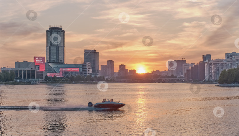 Скачать Городской летний пейзаж. Красивый закат на реке Исеть. Моторная лодка плывет по воде. фотосток Ozero