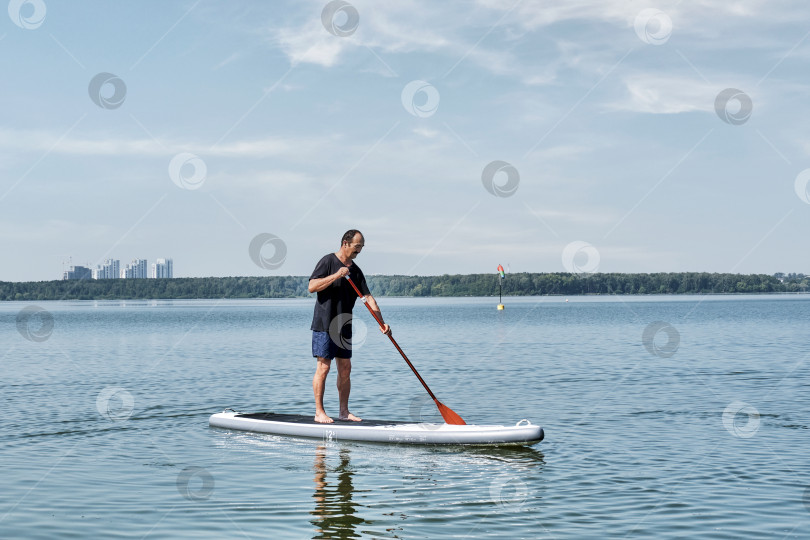 Скачать Пожилой азиат на sup-доске на спокойном озере. фотосток Ozero