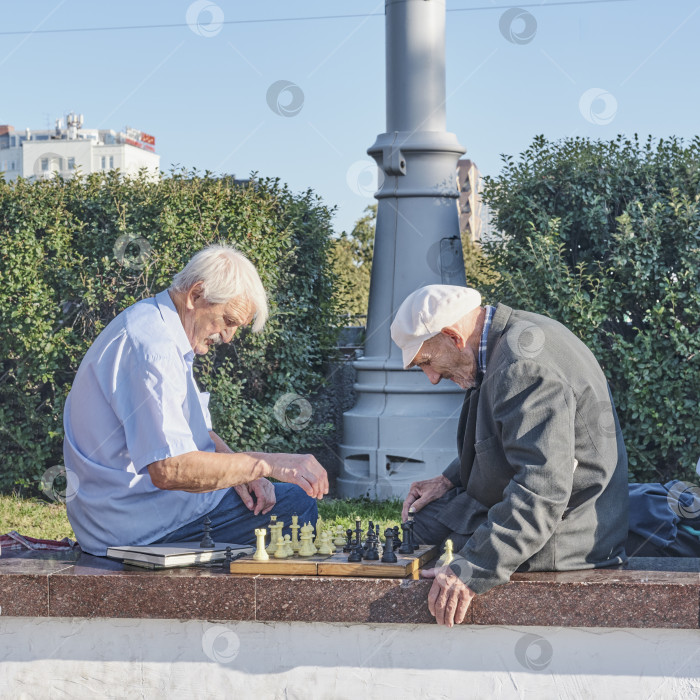 Скачать Двое пожилых мужчин играют в шахматы на городской улице. фотосток Ozero