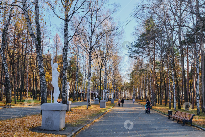 Скачать Поздней осенью люди прогуливаются по аллее городского парка. фотосток Ozero