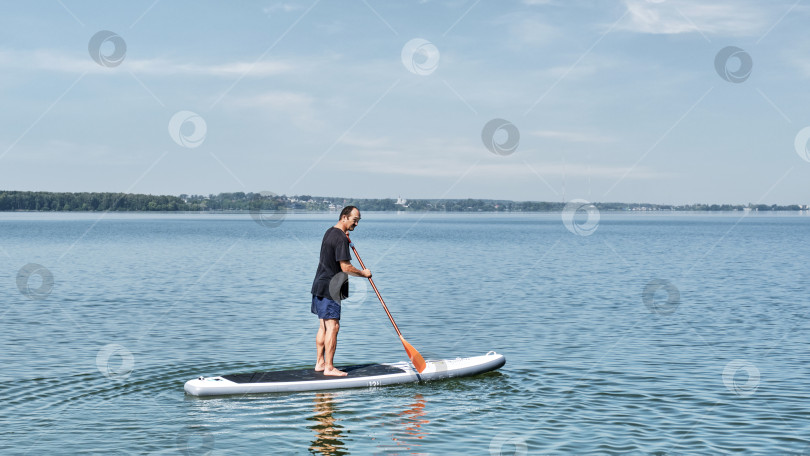 Скачать Пожилой азиат на sup-доске на спокойном озере. фотосток Ozero