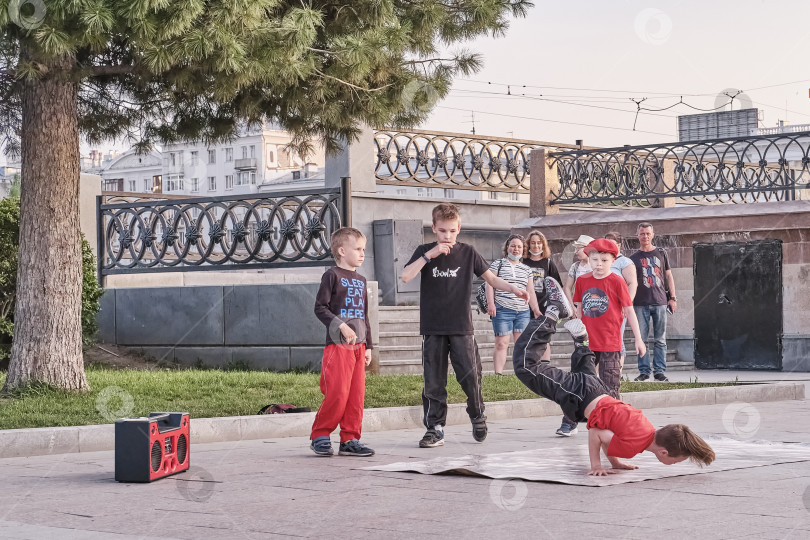 Скачать Мальчики танцуют брейк-данс на городской улице. У нее на руках ребенок-соло. фотосток Ozero