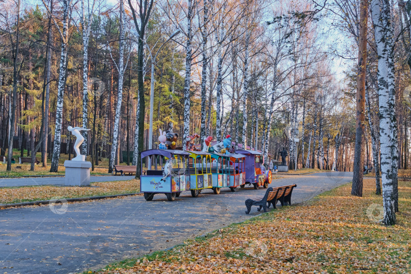 Скачать Екатеринбург, Россия Поздней осенью по аллее городского парка едет почти пустой красочный детский аттракцион "паровозик". фотосток Ozero