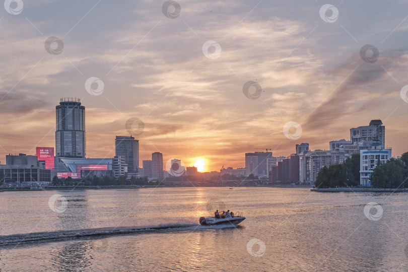 Скачать Городской летний пейзаж. Красивый закат на реке Исеть. Моторная лодка плывет по воде. фотосток Ozero