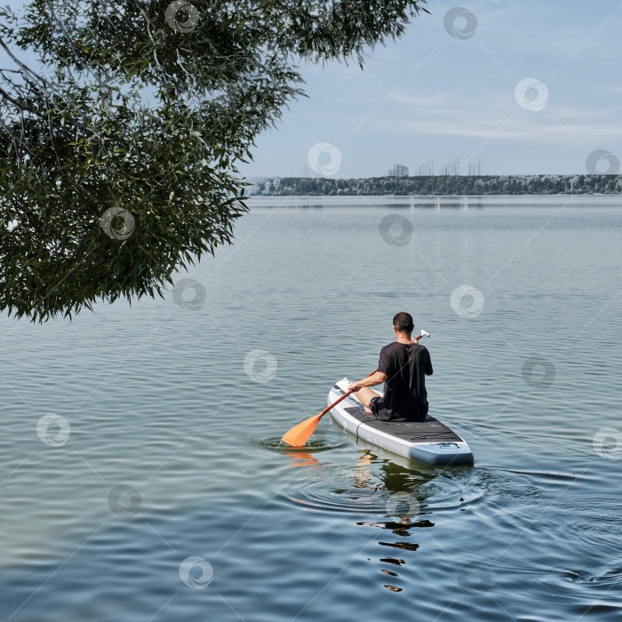 Скачать Пожилой азиат на sup-доске на спокойном озере. фотосток Ozero