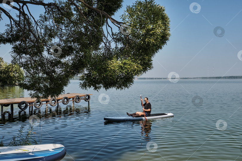 Скачать Пожилой азиат на sup-доске на спокойном озере. фотосток Ozero