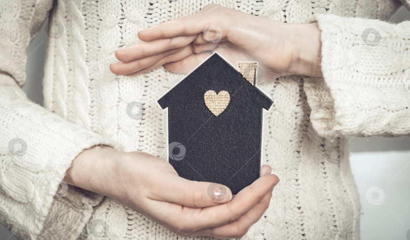 Скачать Женщина держит в руках макет темного дома. Концепция семьи, недвижимости и страхования фотосток Ozero