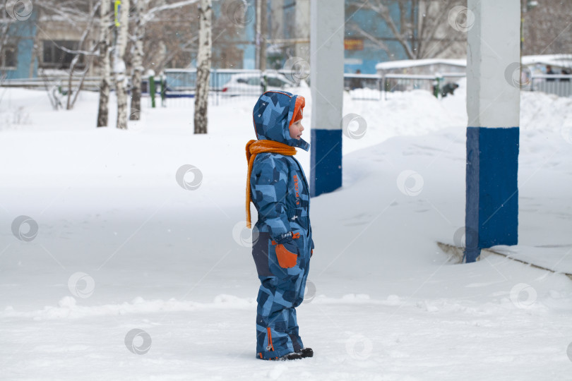 Скачать Маленький ребенок играет зимой в снегу. фотосток Ozero