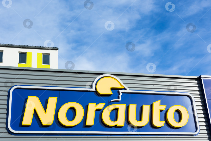 Скачать Логотип бренда Norauto на фоне ярко-голубого неба фотосток Ozero