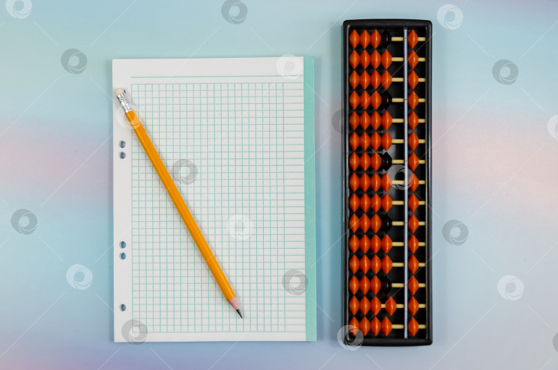 Скачать Тетрадный лист в клетку, карандаш и счеты для ментальной арифметики на цветном фоне фотосток Ozero