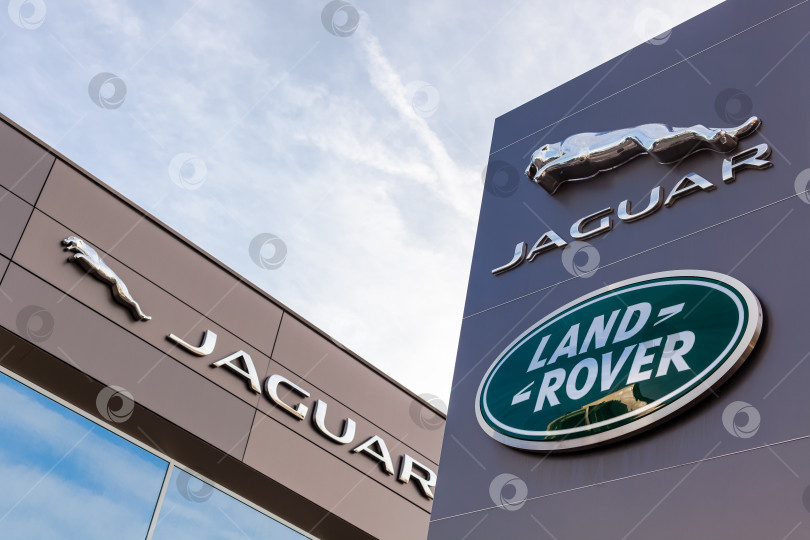 Скачать Логотип бренда Jaguar Land Rover на фоне голубого неба фотосток Ozero