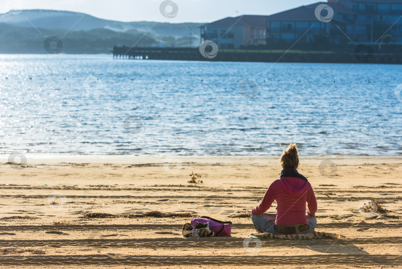 Скачать Девушка сидит на песке и смотрит на воду фотосток Ozero
