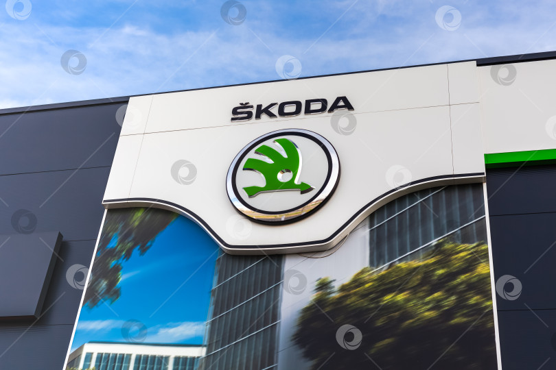 Скачать Логотип бренда Skoda на фоне ярко-голубого неба фотосток Ozero