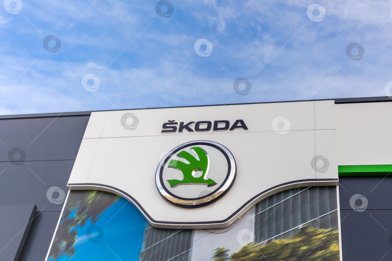 Скачать Логотип бренда Skoda на фоне ярко-голубого неба фотосток Ozero
