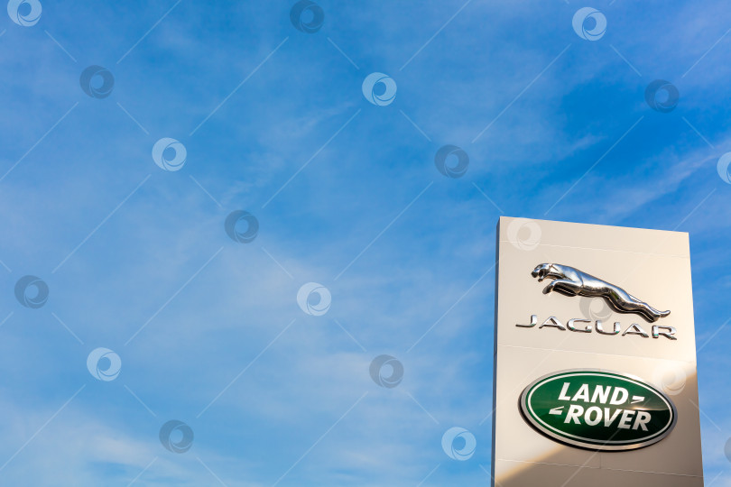 Скачать Логотип бренда Jaguar Land Rover на фоне голубого неба фотосток Ozero