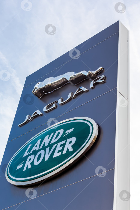 Скачать Логотип бренда Jaguar Land Rover на фоне голубого неба фотосток Ozero