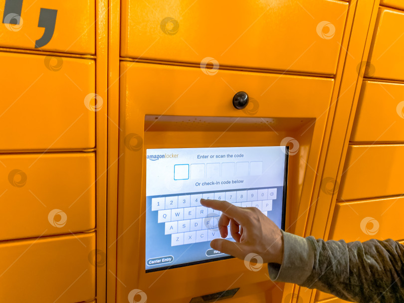 Скачать Мужчина пользуется шкафчиком Amazon Locker в торговом центре фотосток Ozero