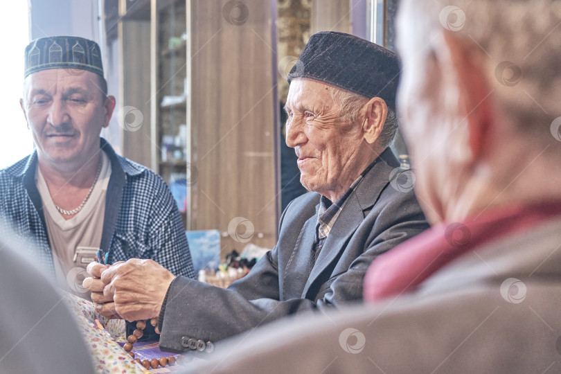 Скачать Мулла, произносящий проповедь, улыбается среди жителей деревни. фотосток Ozero