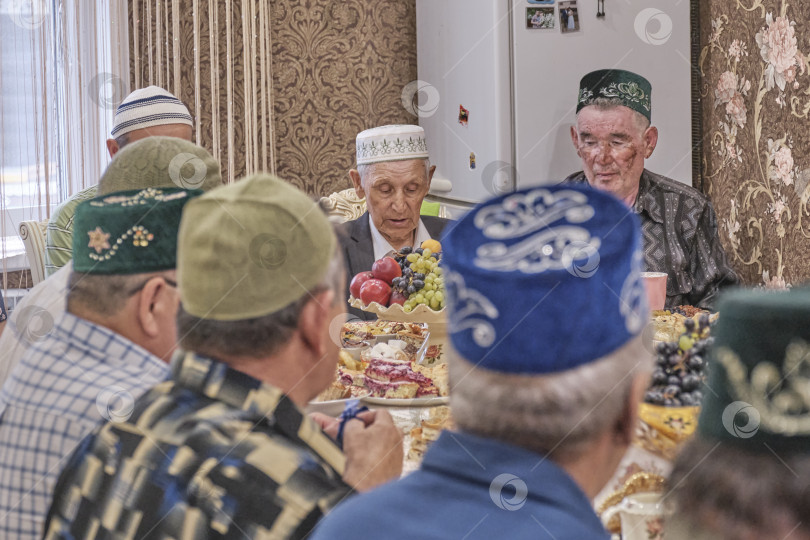 Скачать Жители сибирской деревни отмечают мусульманский праздник Курбан-байрам за домашним столом. Мулла читает молитву. Ид аль-Адха фотосток Ozero