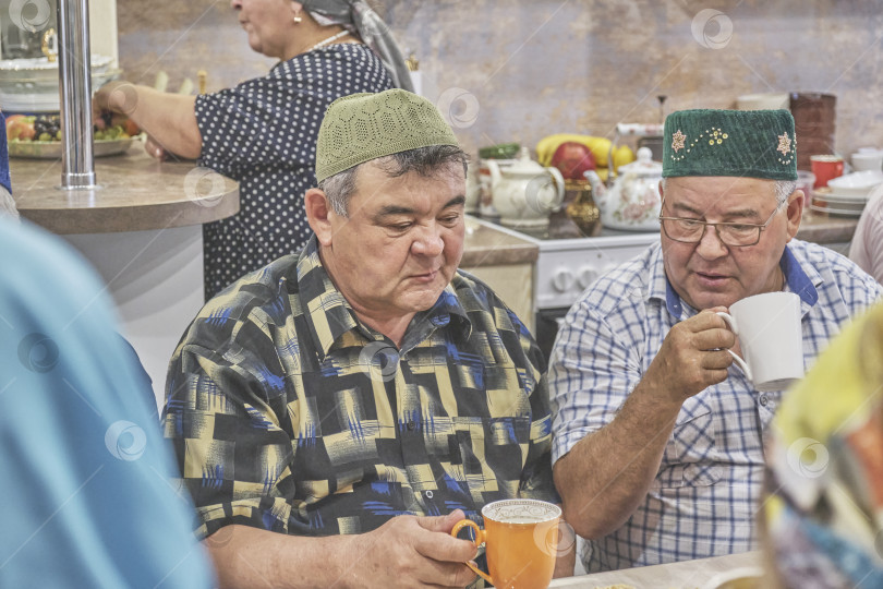 Скачать Жители сибирской деревни отмечают мусульманский праздник Курбан-байрам за домашним столом. Беседуют двое пожилых жителей деревни. Курбан-Байрам фотосток Ozero