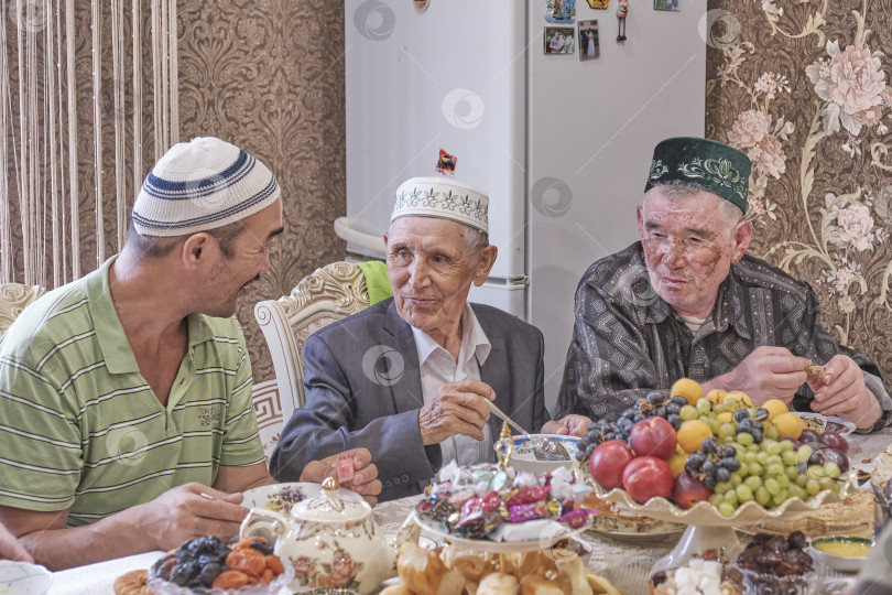 Скачать Жители сибирской деревни отмечают мусульманский праздник Курбан-байрам за домашним столом. Мулла беседует с жителями деревни. Курбан-Байрам фотосток Ozero