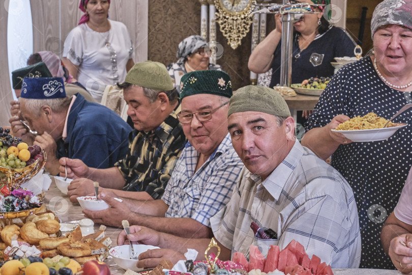 Скачать Жители сибирской деревни отмечают мусульманский праздник Курбан-байрам за домашним столом. Сельчане едят. Курбан-Байрам фотосток Ozero