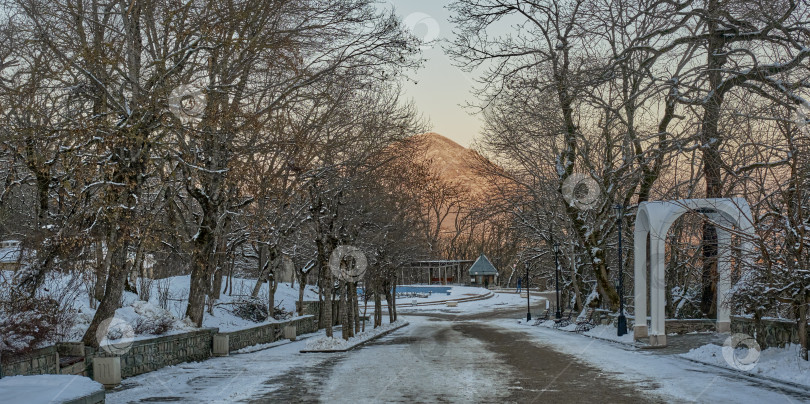 Скачать Зимний вечерний пейзаж. Аллея в заснеженном парке города Железноводска. Россия фотосток Ozero