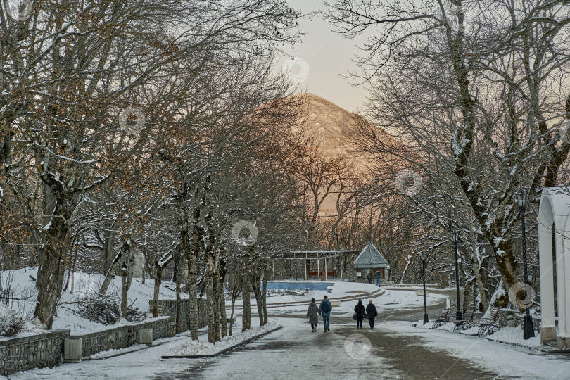 Скачать Зимний вечерний пейзаж. Аллея в заснеженном парке города Железноводска. Россия фотосток Ozero