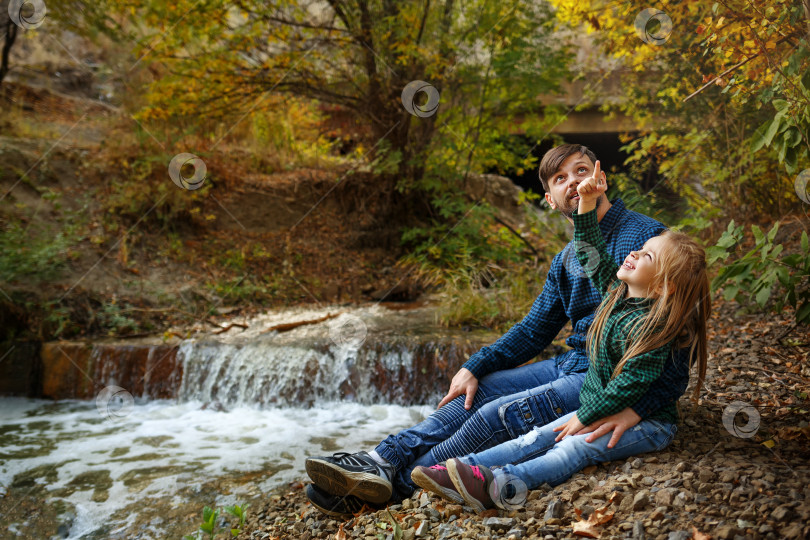 Скачать Отец и дочь сидят у водопада фотосток Ozero