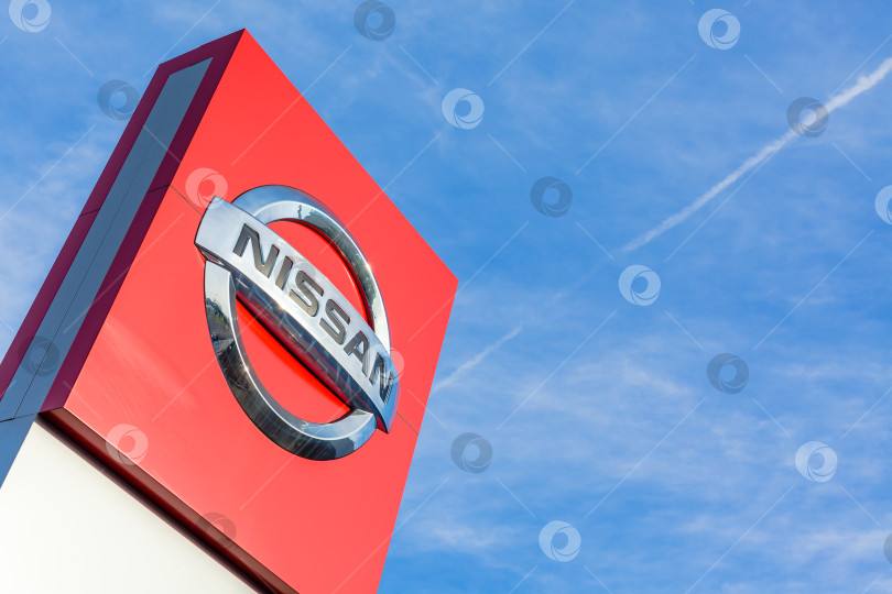 Скачать Логотип бренда Nissan на фоне ярко-голубого неба фотосток Ozero