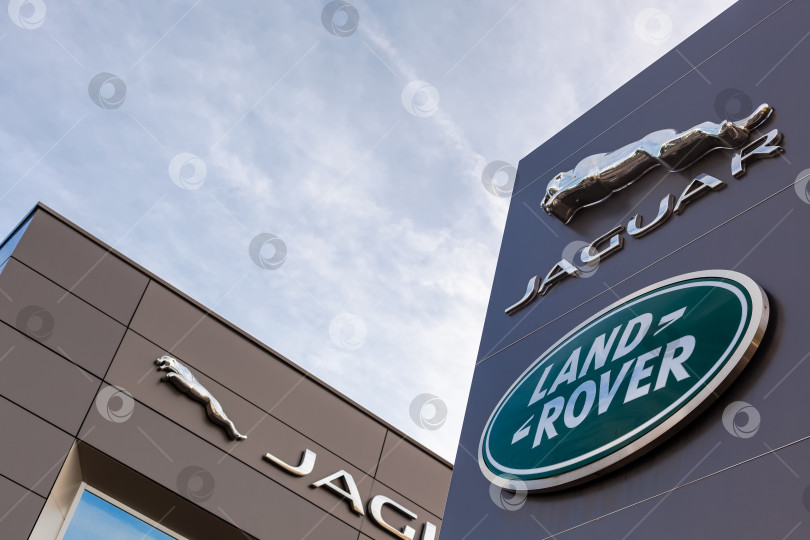 Скачать Логотип бренда Jaguar Land Rover на фоне голубого неба фотосток Ozero