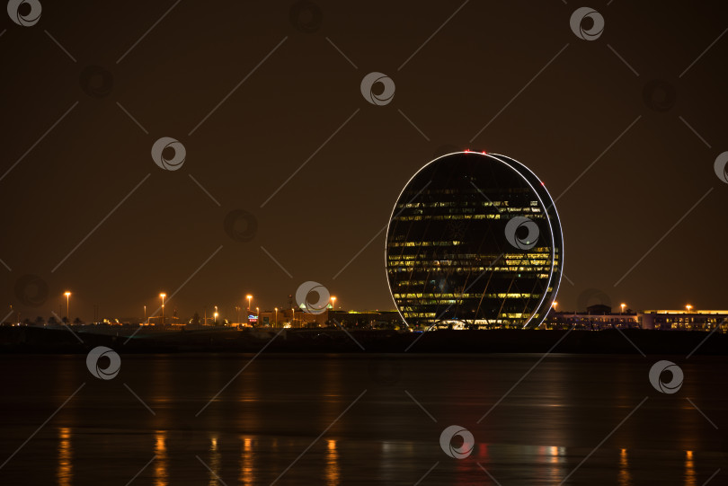 Скачать Вид на здание штаб-квартиры Aldar и ночной пейзаж Абу-Даби фотосток Ozero
