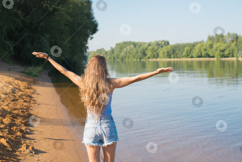 Скачать Женщина с длинными волосами стоит на пляже у водоема фотосток Ozero