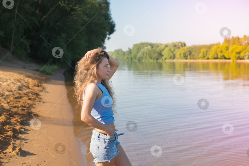 Скачать Женщина с длинными волосами стоит на пляже у водоема фотосток Ozero