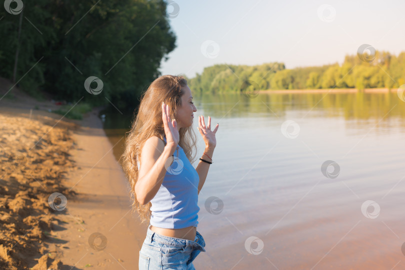 Скачать Женщина с длинными волосами стоит на пляже у водоема фотосток Ozero