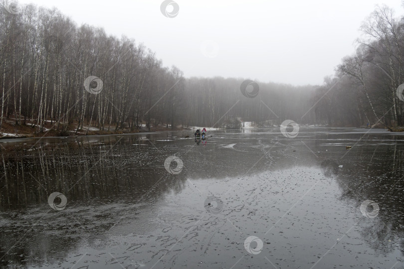 Скачать Два рыбака на льду недавно замерзшего пруда. фотосток Ozero