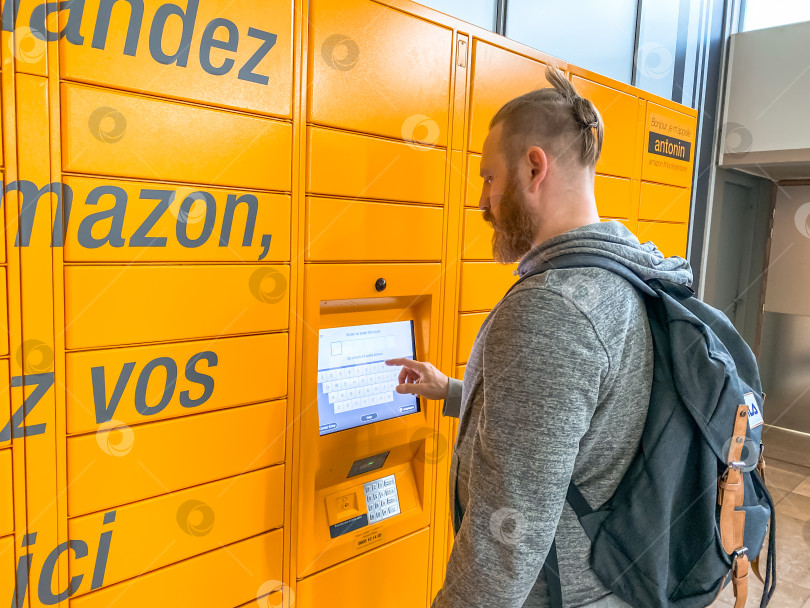Скачать Мужчина пользуется шкафчиком Amazon Locker в торговом центре фотосток Ozero