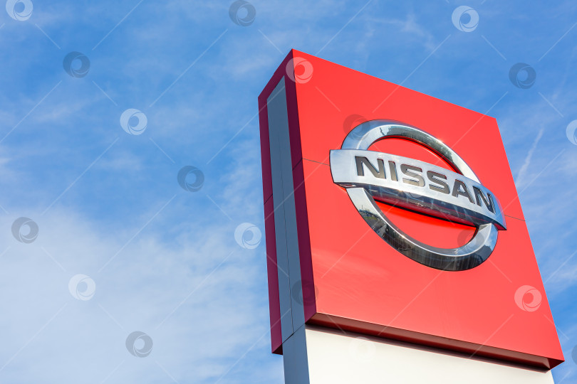 Скачать Логотип бренда Nissan на фоне ярко-голубого неба фотосток Ozero