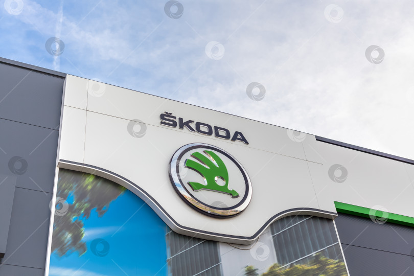 Скачать Логотип бренда Skoda на фоне ярко-голубого неба фотосток Ozero